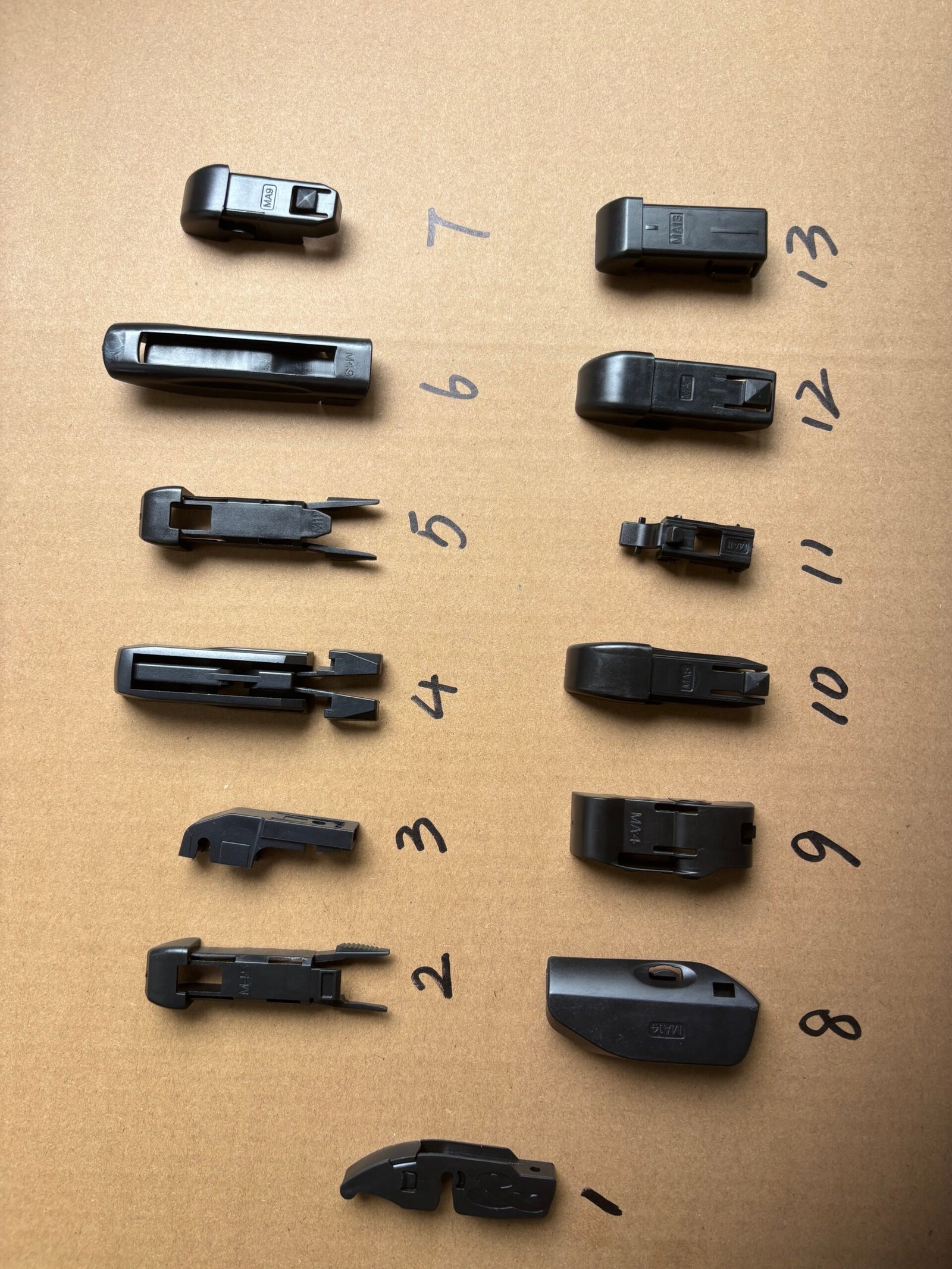 Wiper blade adapter clips laid out with numbered positions for connector coverage